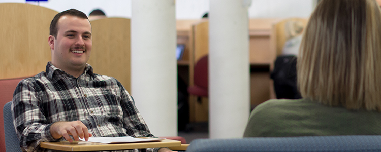 student in plaid shirt talking in library